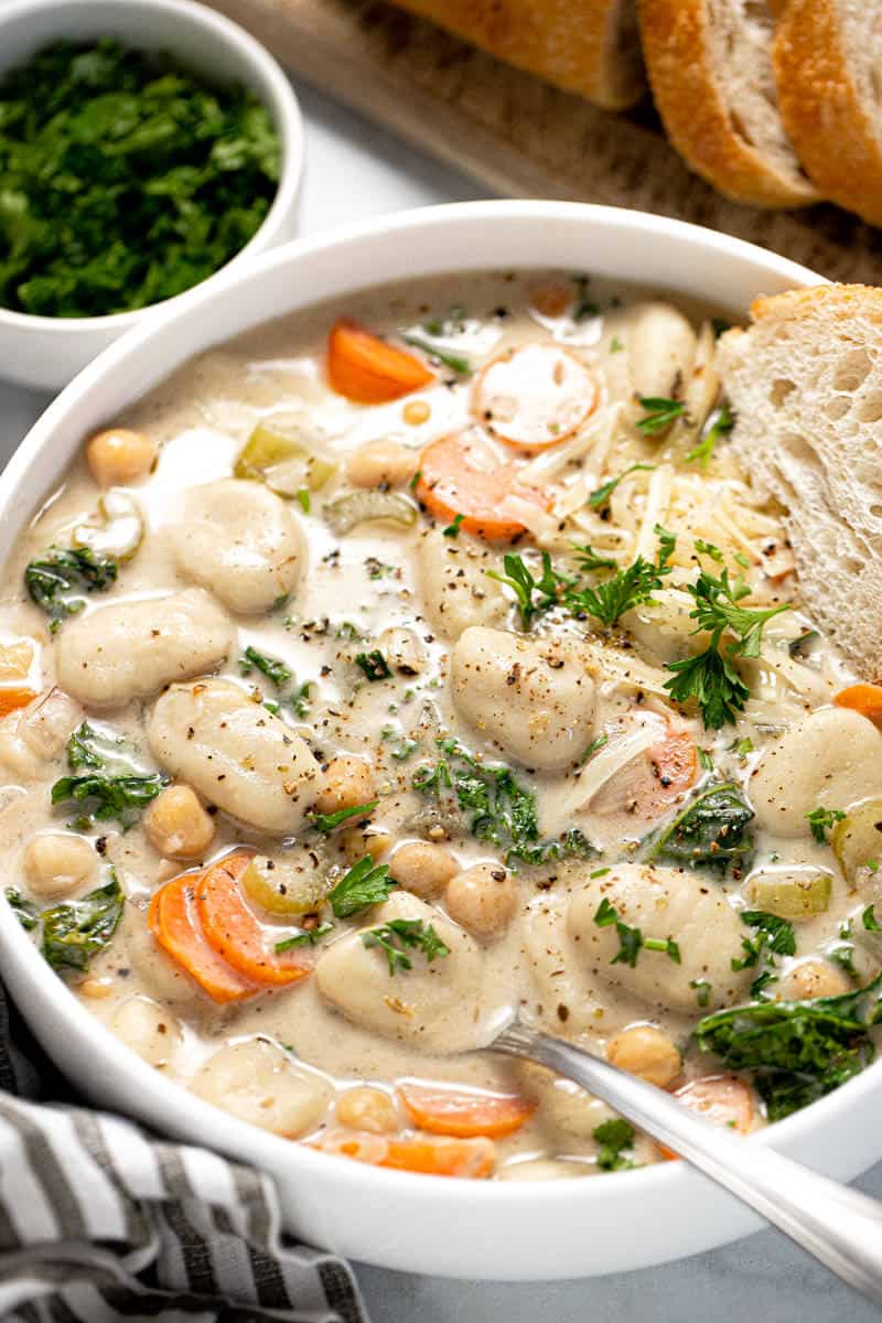 Large white bowl with creamy vegan gnocchi soup garnished with fresh chopped parsley 