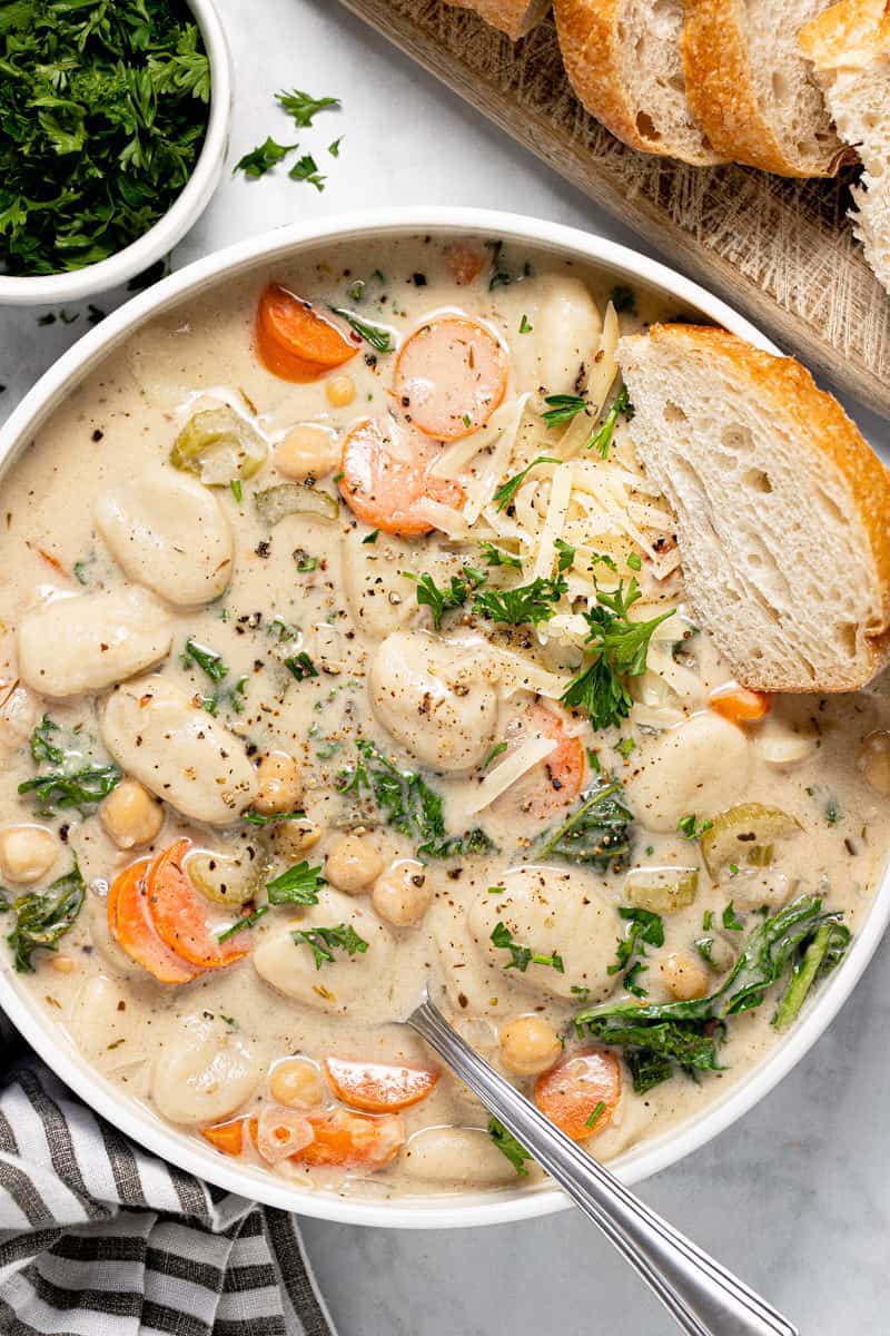 Large white bowl with creamy vegan gnocchi soup garnished with fresh chopped parsley