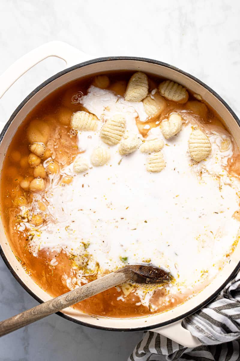 Large white pot filled with ingredients to make creamy vegan gnocchi soup