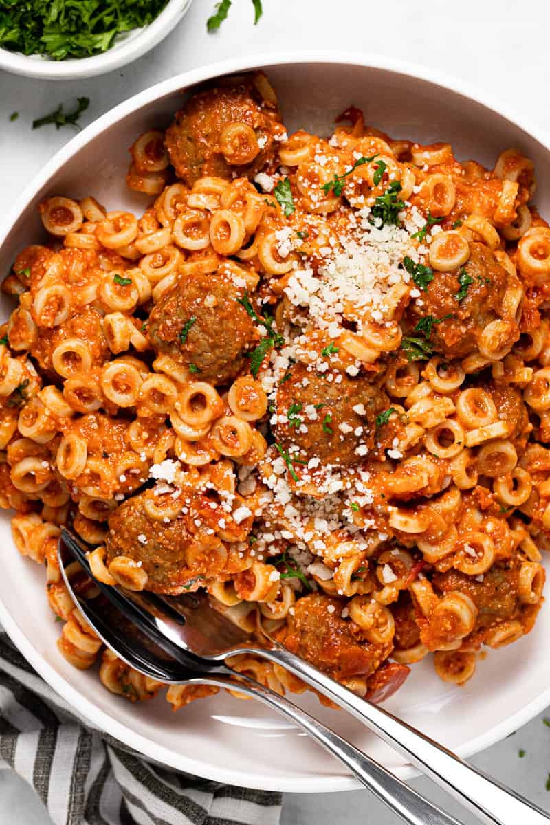 White plate filled with homemade spaghettios garnished with Parmesan and parsley