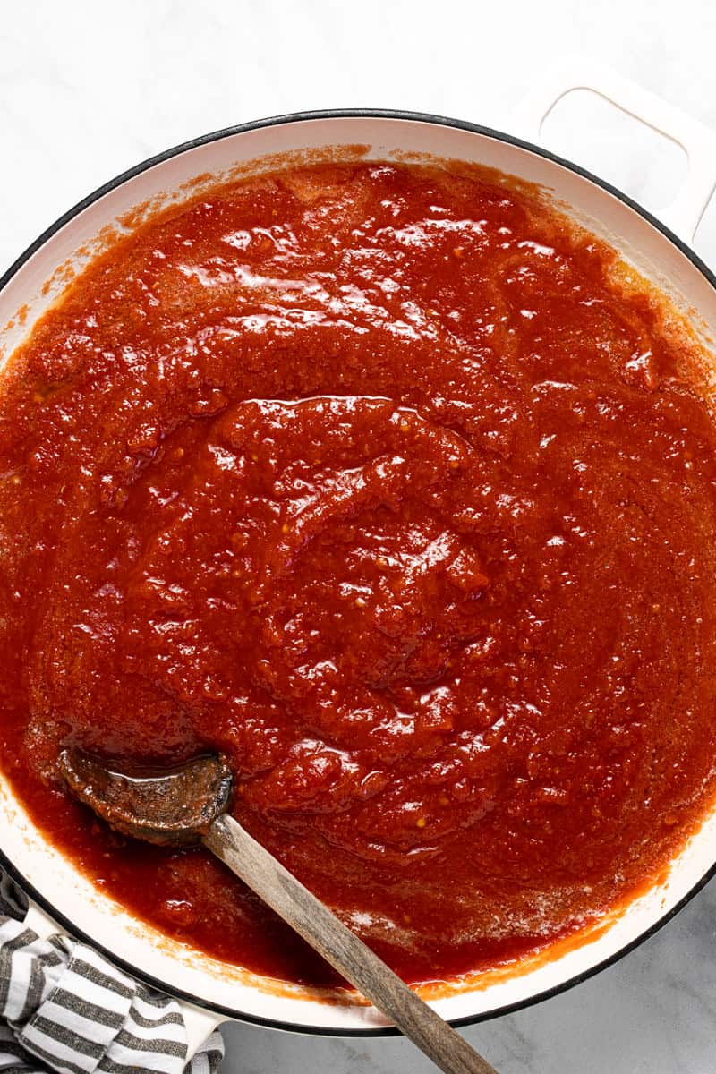 Large white pot filled with melted butter and crushed tomatoes