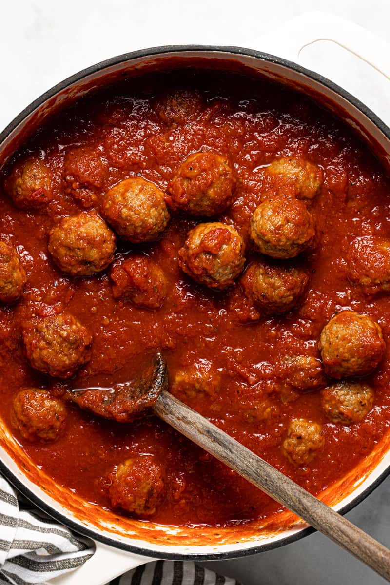 Large white pot filled with crushed tomatoes and meatballs