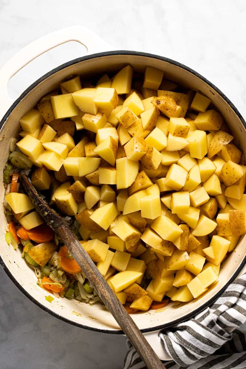 Large white pot with ingredients to make potato leek soup