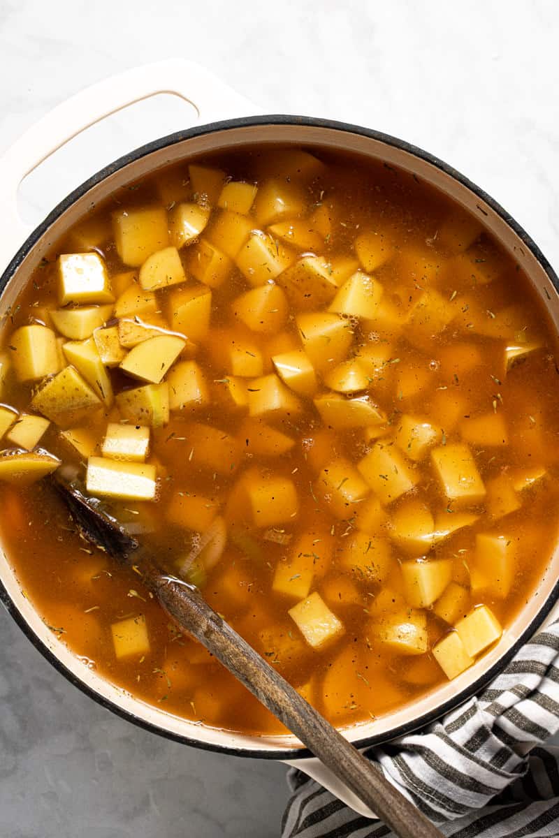 Large white pot with ingredients to make potato leek soup