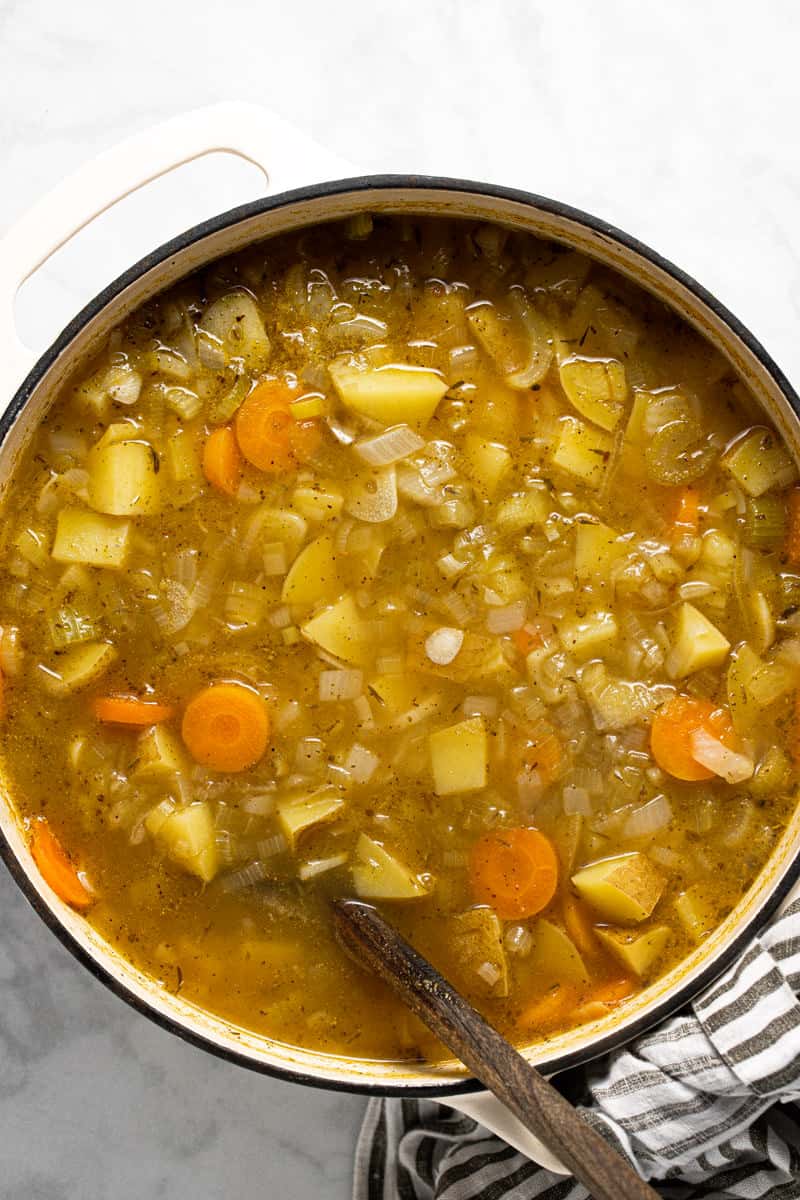 Large white pot with ingredients to make potato leek soup