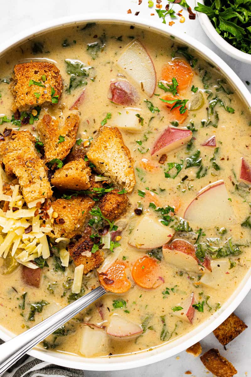 Overhead shot of a white bowl filled with potato kale soup and homemade croutons