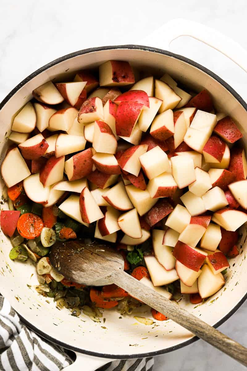 Large white pot with ingredients to make potato kale soup