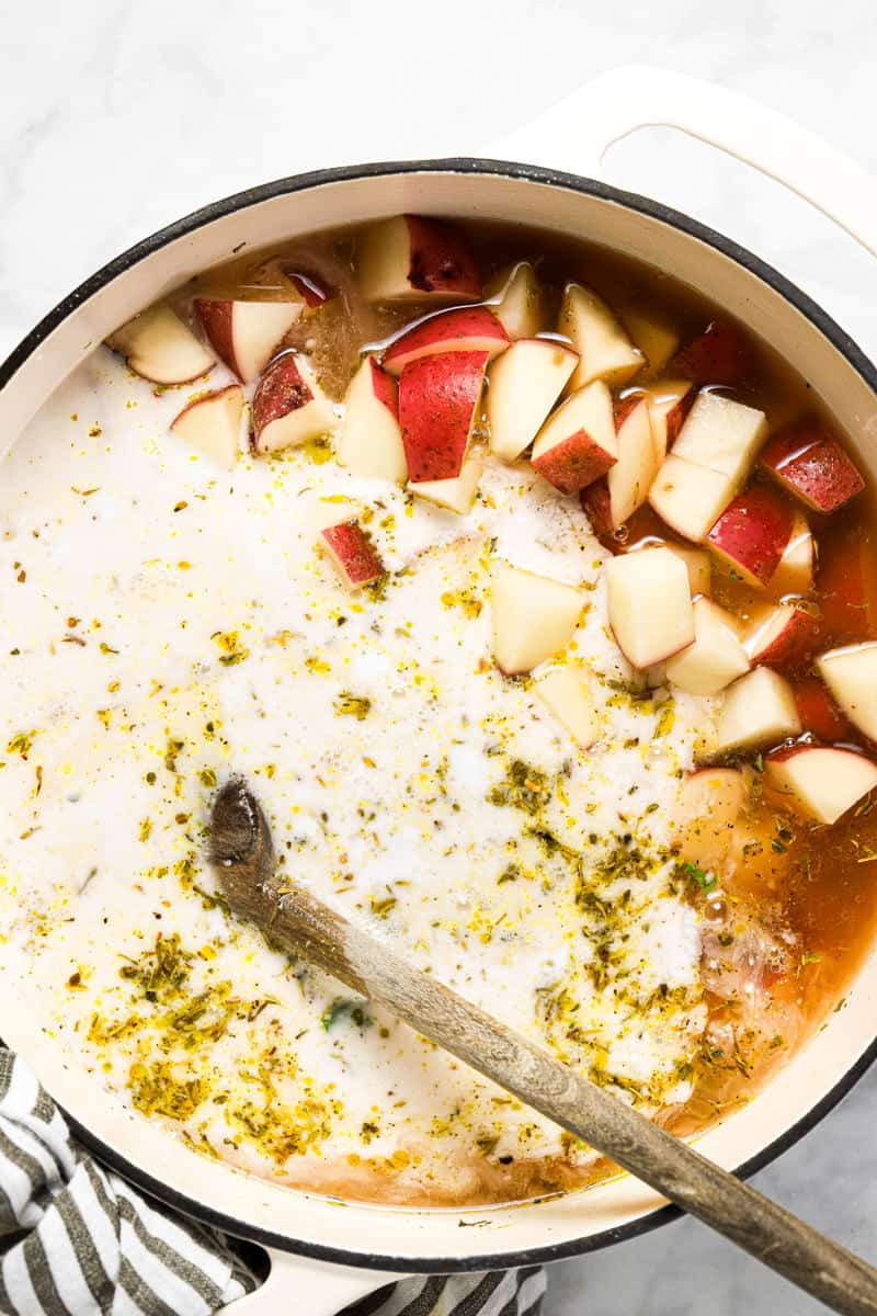 Large white pot with ingredients to make potato kale soup