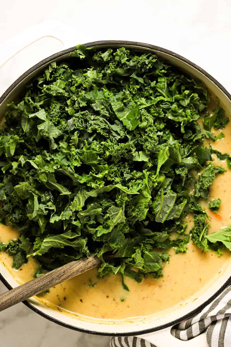 Large white pot with ingredients to make potato kale soup