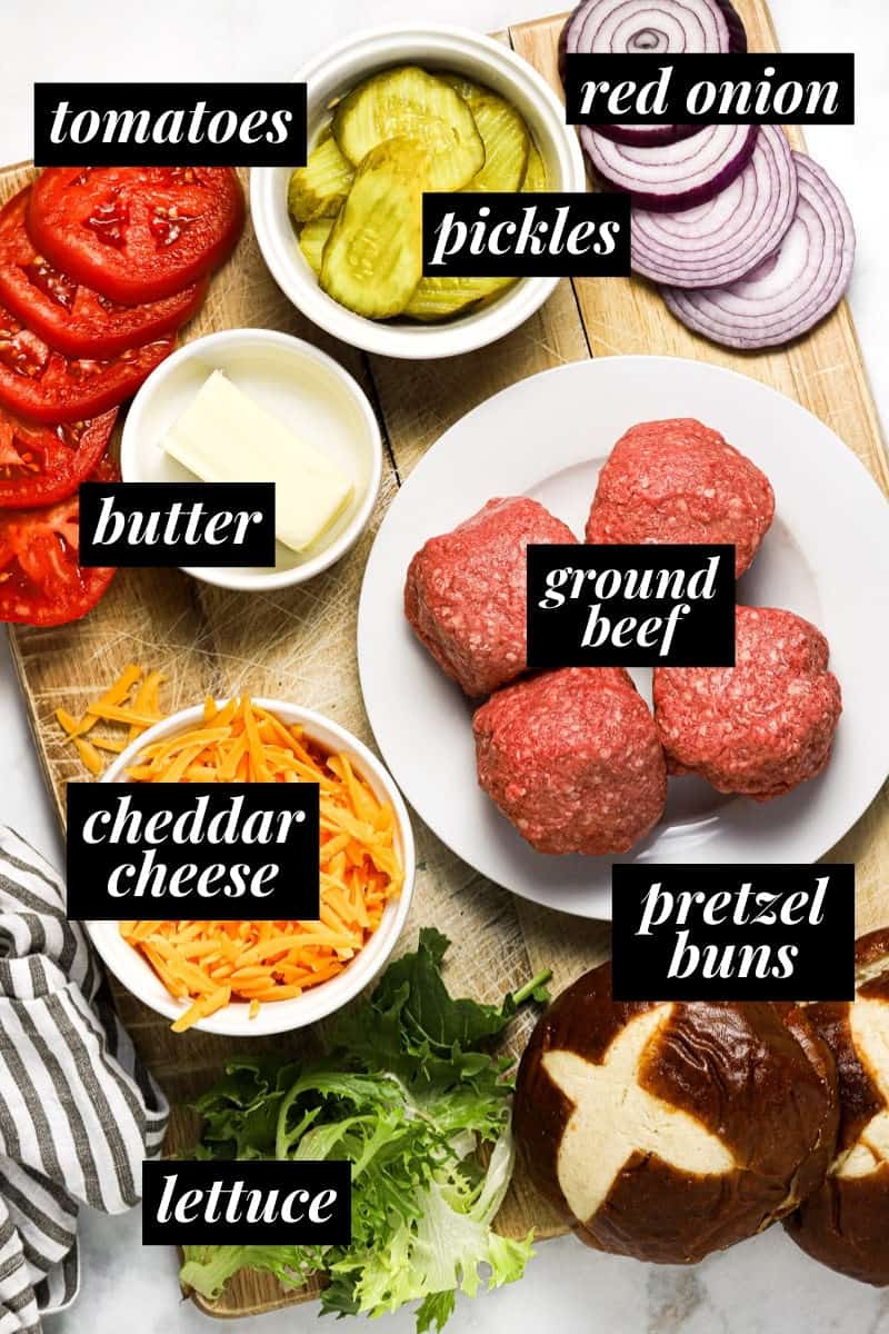 White marble counter top with cutting board filled with ingredients to make homemade smash burgers 