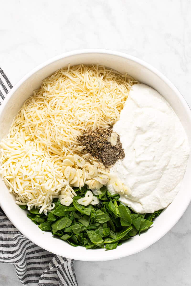 Large white bowl with ingredients to make lasagna filling
