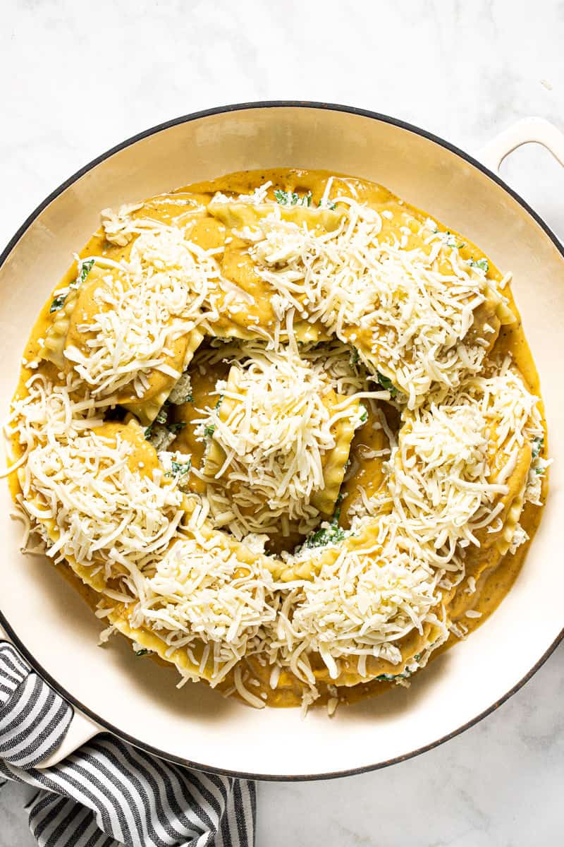 Squash lasagna rolls up in a white pan topped with shredded cheese