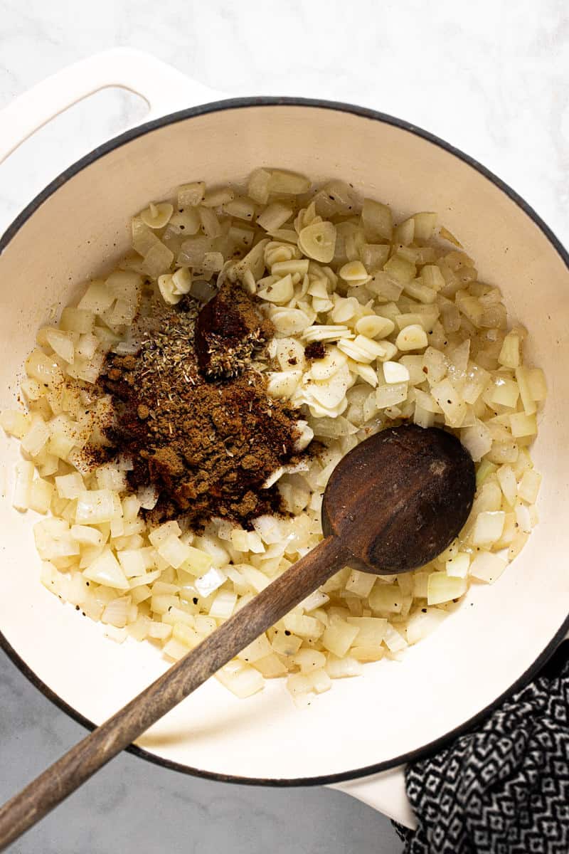 White pot filled with sautéed onions sliced garlic and spices
