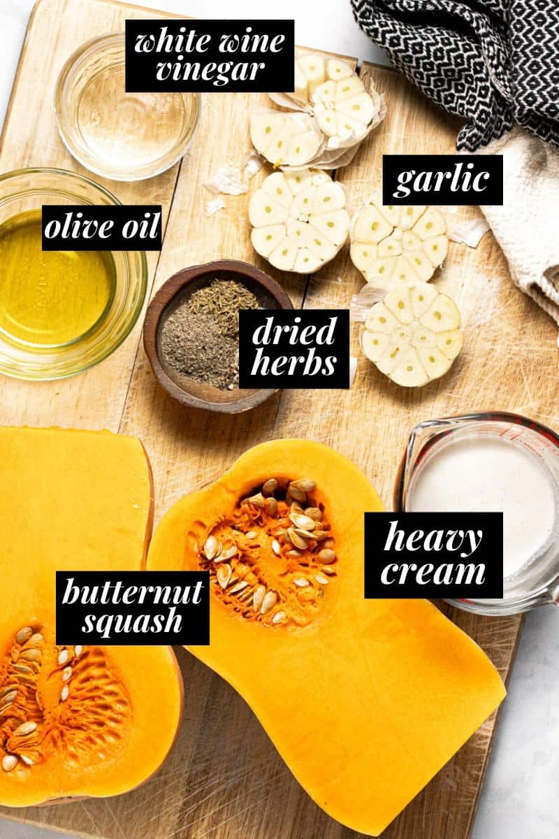 A large wooden cutting board with ingredients to make roasted squash and garlic cream sauce