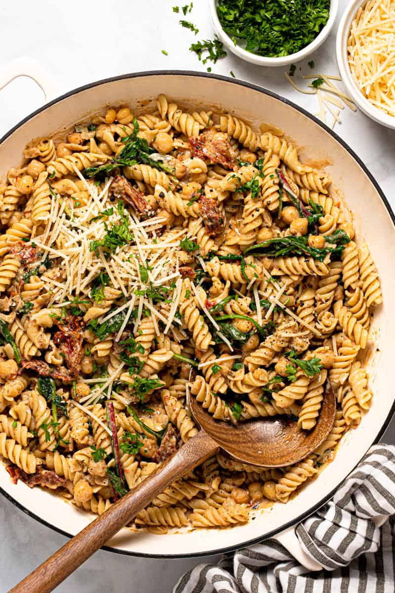 Large pan filled with creamy vegan sun-dried tomato pasta topped with Parmesan cheese
