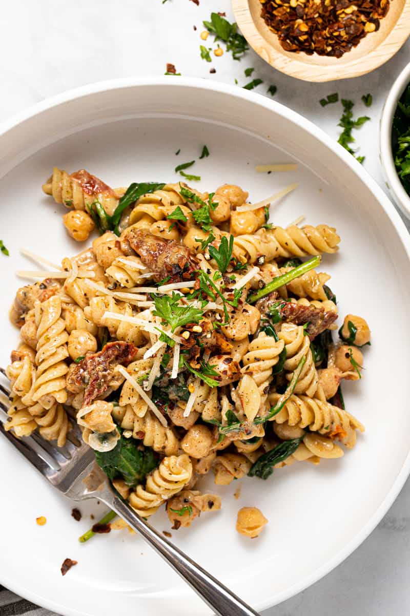 Large white bowl filled with homemade creamy Tuscan pasta topped with fresh parsley 