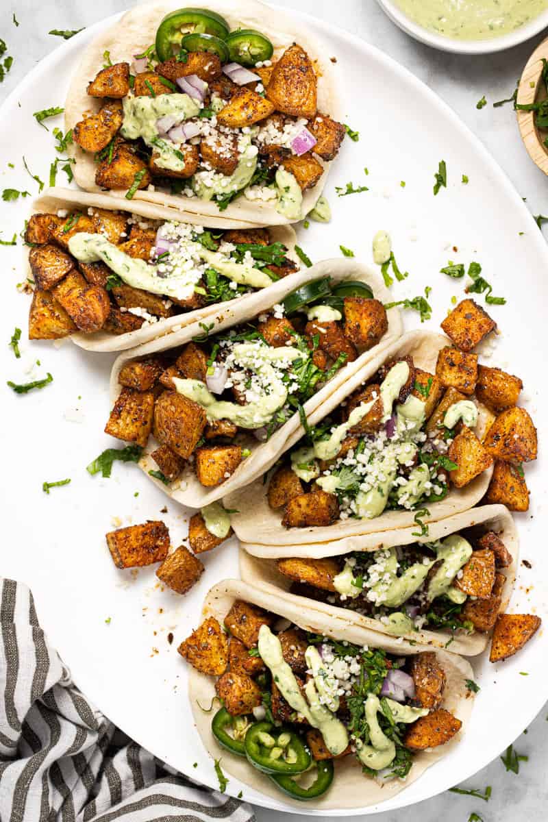 White platter with vegan potato tacos garnished with fresh cilantro