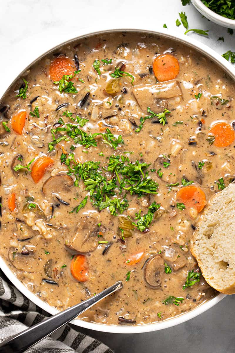 Overhead shot of a large white bowl filled with homemade vegan wild rice soup garnished with fresh parsley 