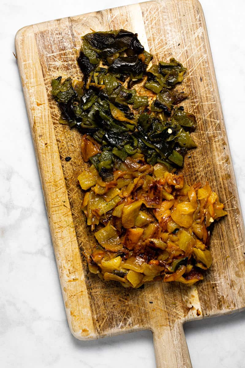 Wooden cutting board with diced roasted peppers on it