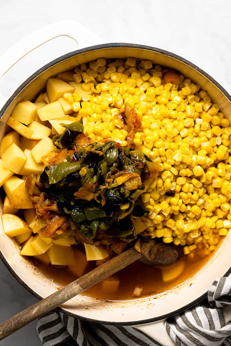 Large white pot with ingredients to make vegan corn chowder