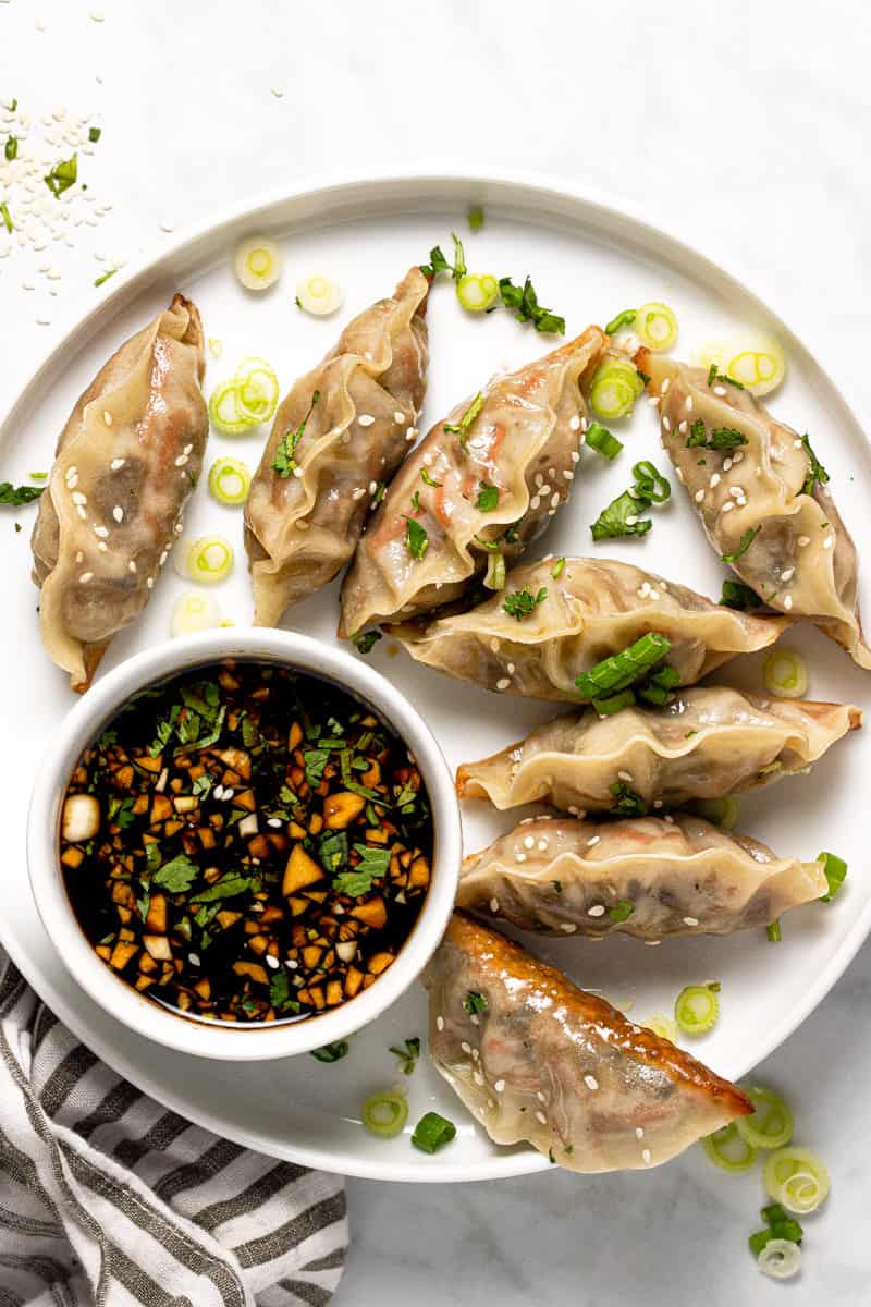 White plate filled with homemade vegetable dumplings garnished with green onion