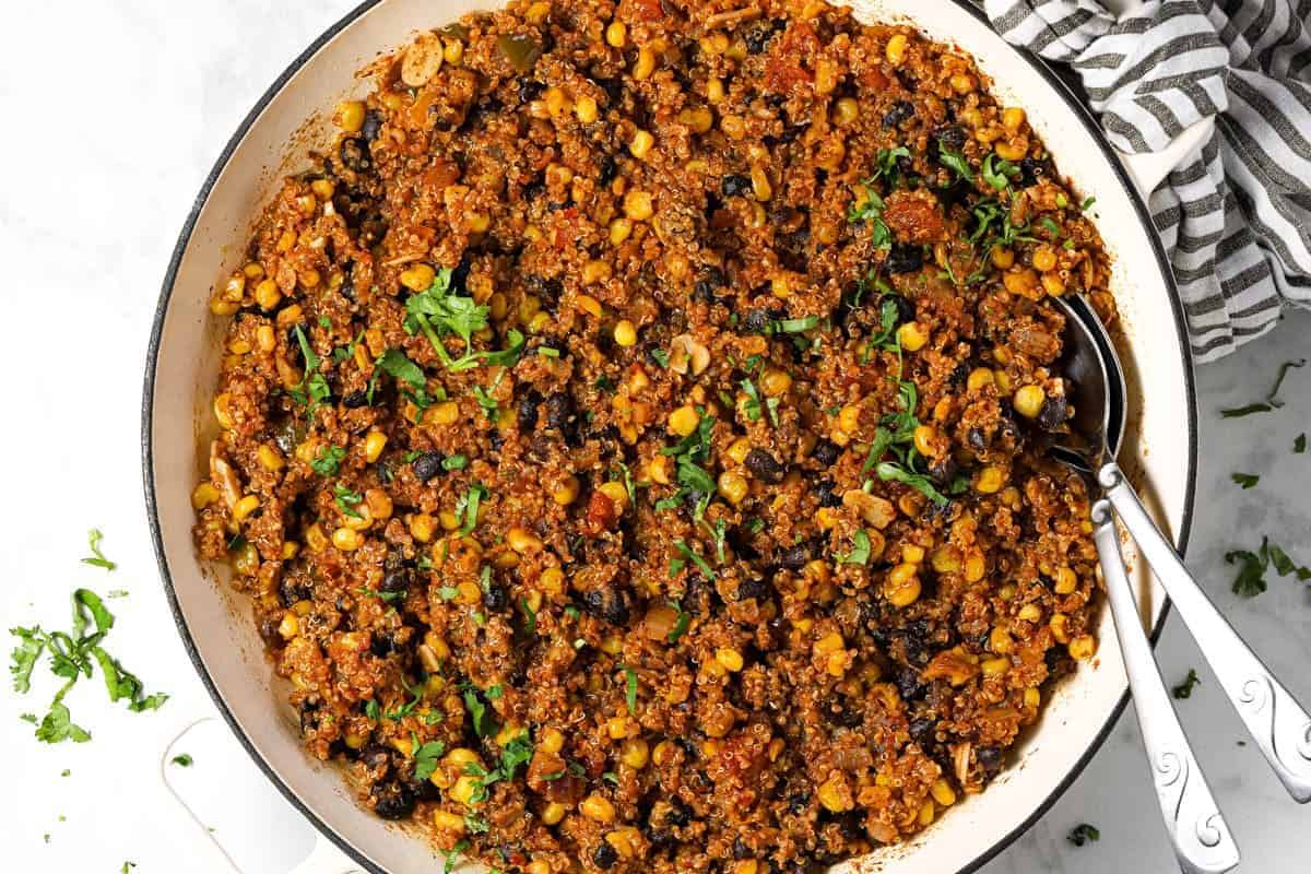 Mexican quinoa in a large white pan garnished with fresh chopped cilantro