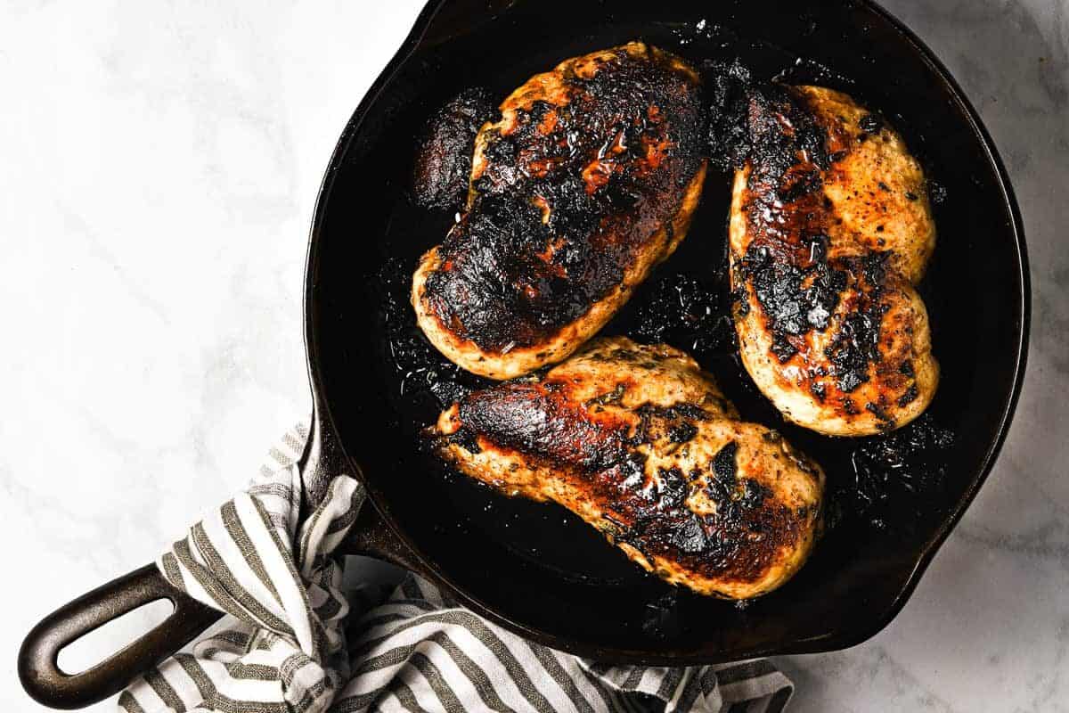 Overhead shot of a cast iron pan with golden brown sauteed chicken breast 