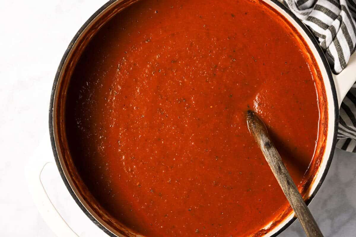 Large white pot with ingredients to make homemade tomato basil soup 
