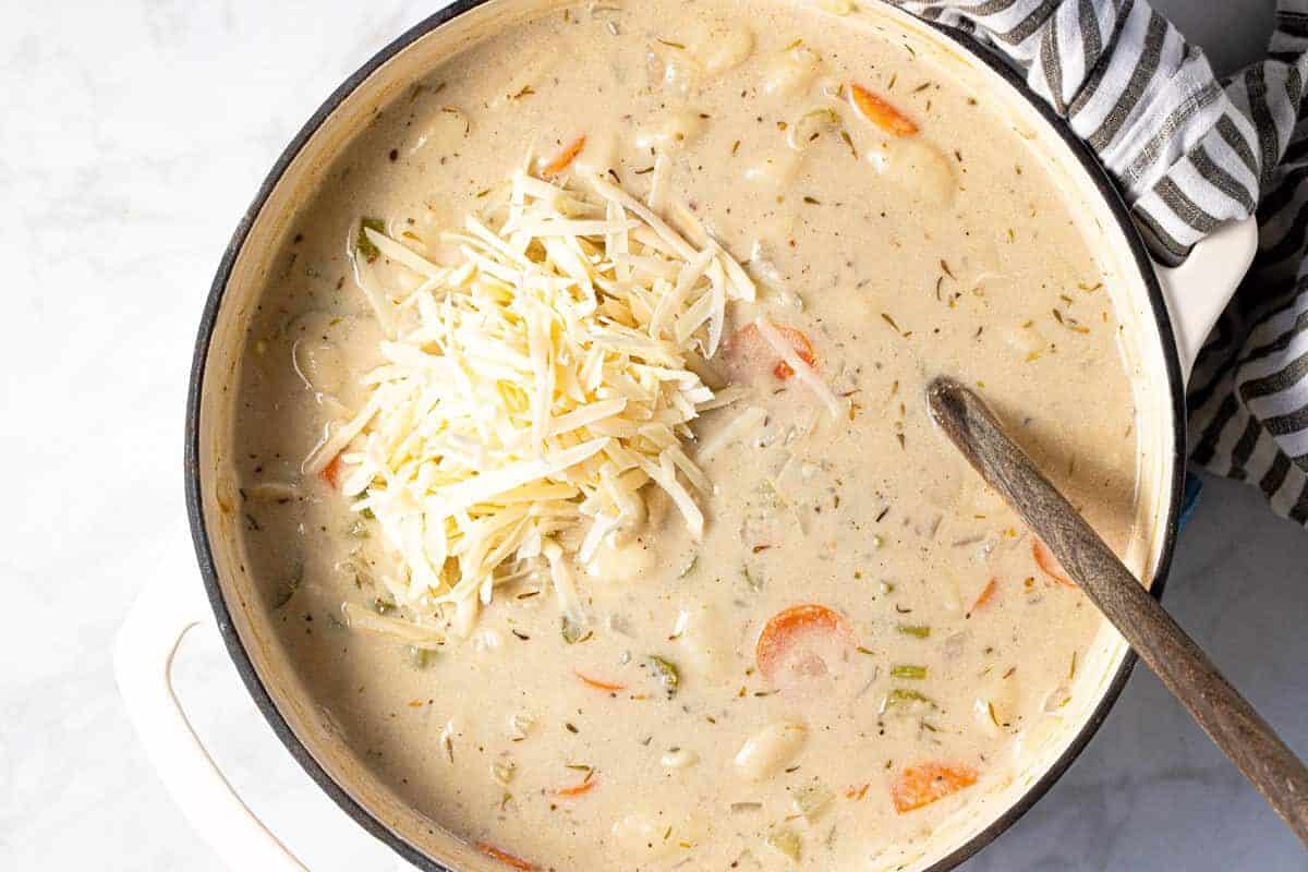 Large white pot filled with ingredients to make creamy vegan gnocchi soup