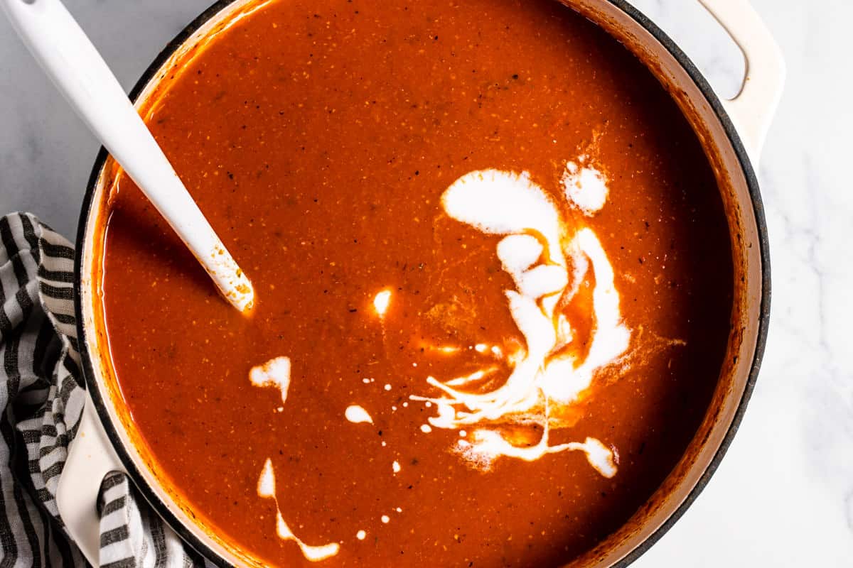 Large white pot filled with ingredients to make creamy vegan tomato soup 