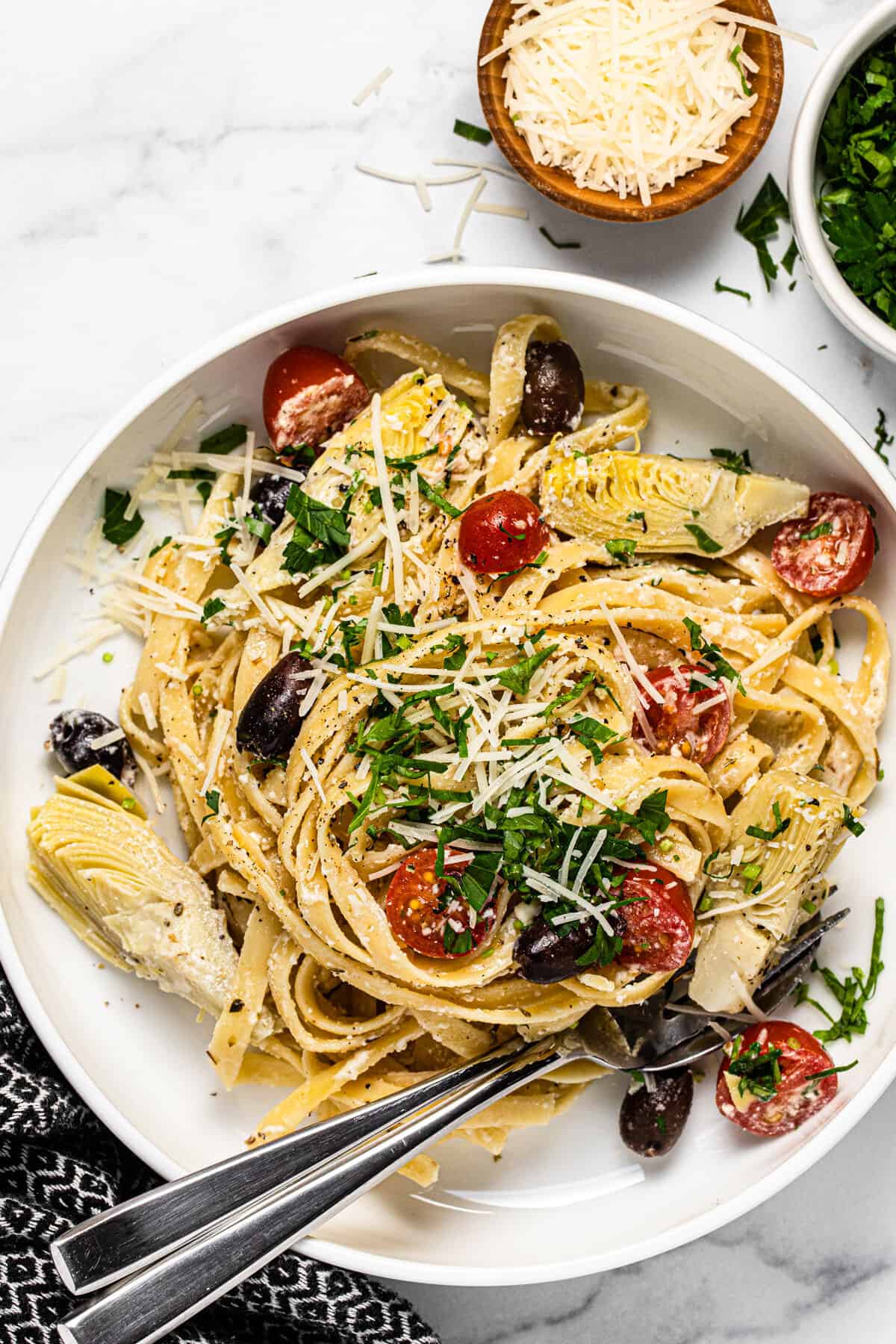 Large white bowl filled with Greek pasta garnished with fresh chopped parsley
