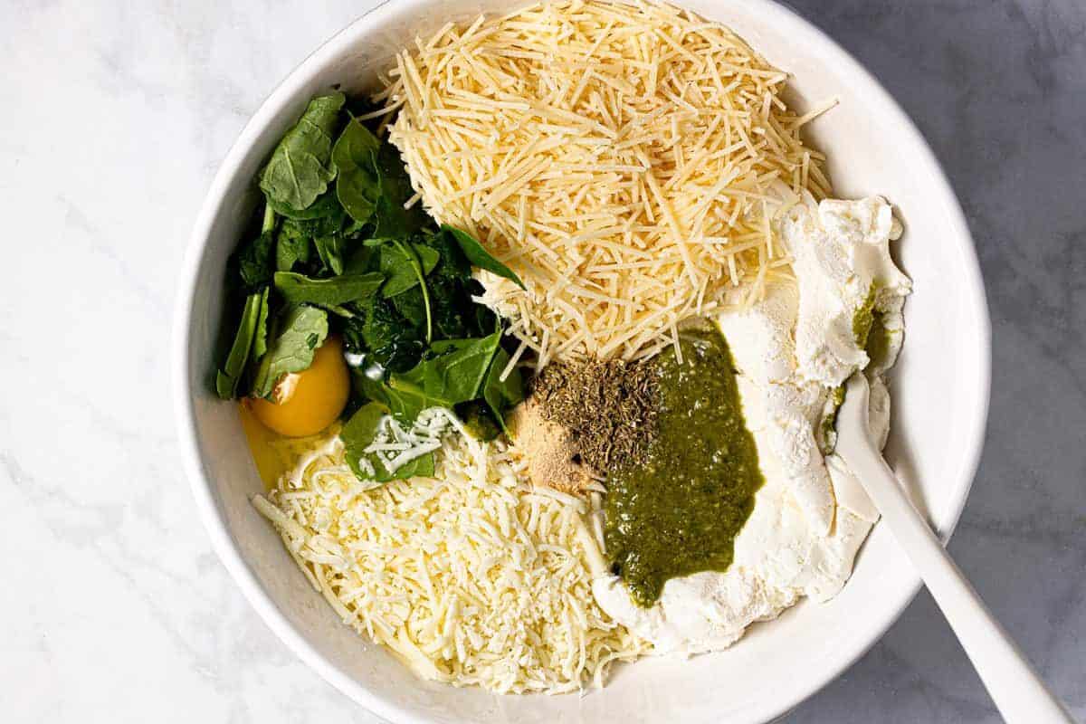 Large white bowl filled with ingredients to make manicotti filling