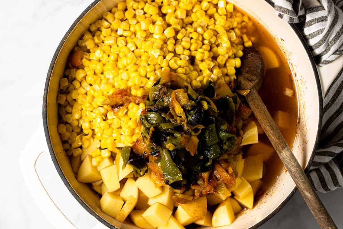Large white pot with ingredients to make vegan corn chowder