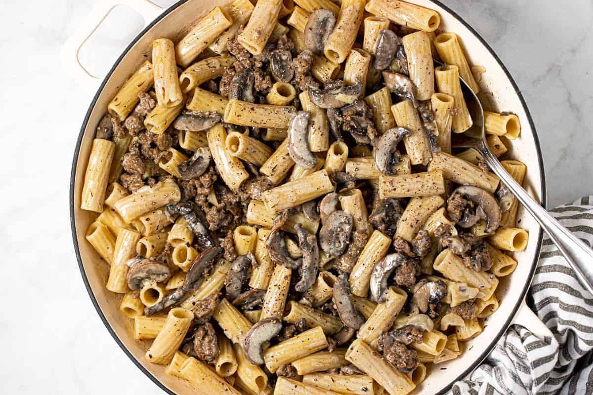Large pan filled with creamy sausage and mushroom pasta 