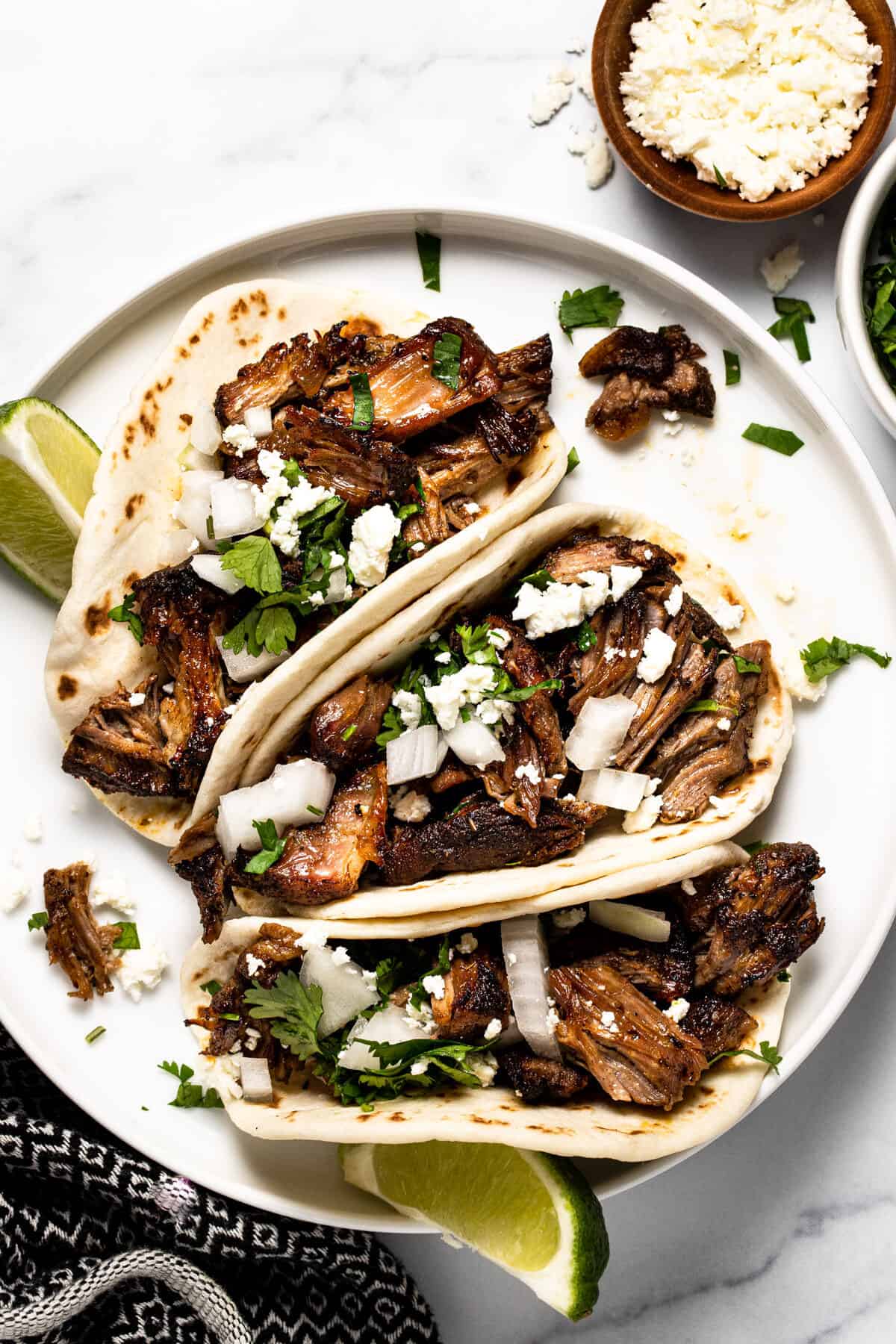 White plate filled with beer braised slow cooker pork carnitas tacos