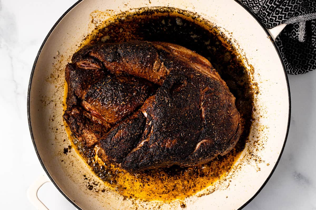 Seared pork roast in a large white pan 