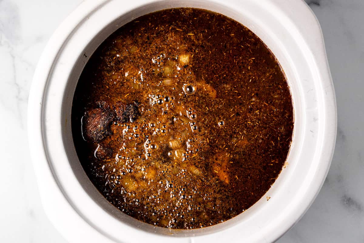 Crock pot filled with ingredients to make beer braised pork carnitas