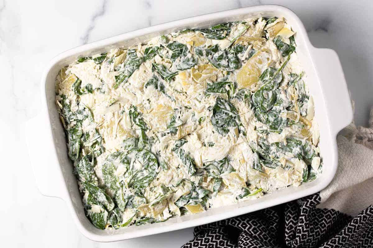 Spinach and artichoke dip spread in a large baking dish