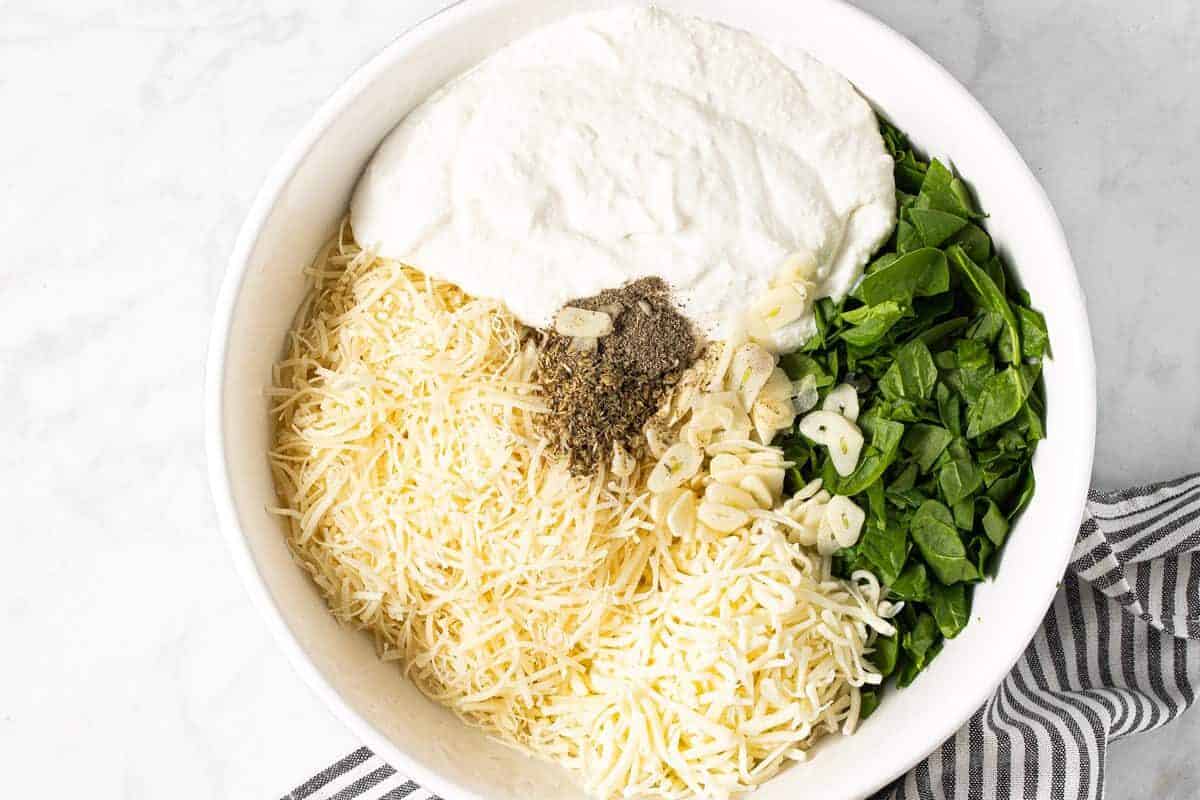 Large white bowl with ingredients to make lasagna filling