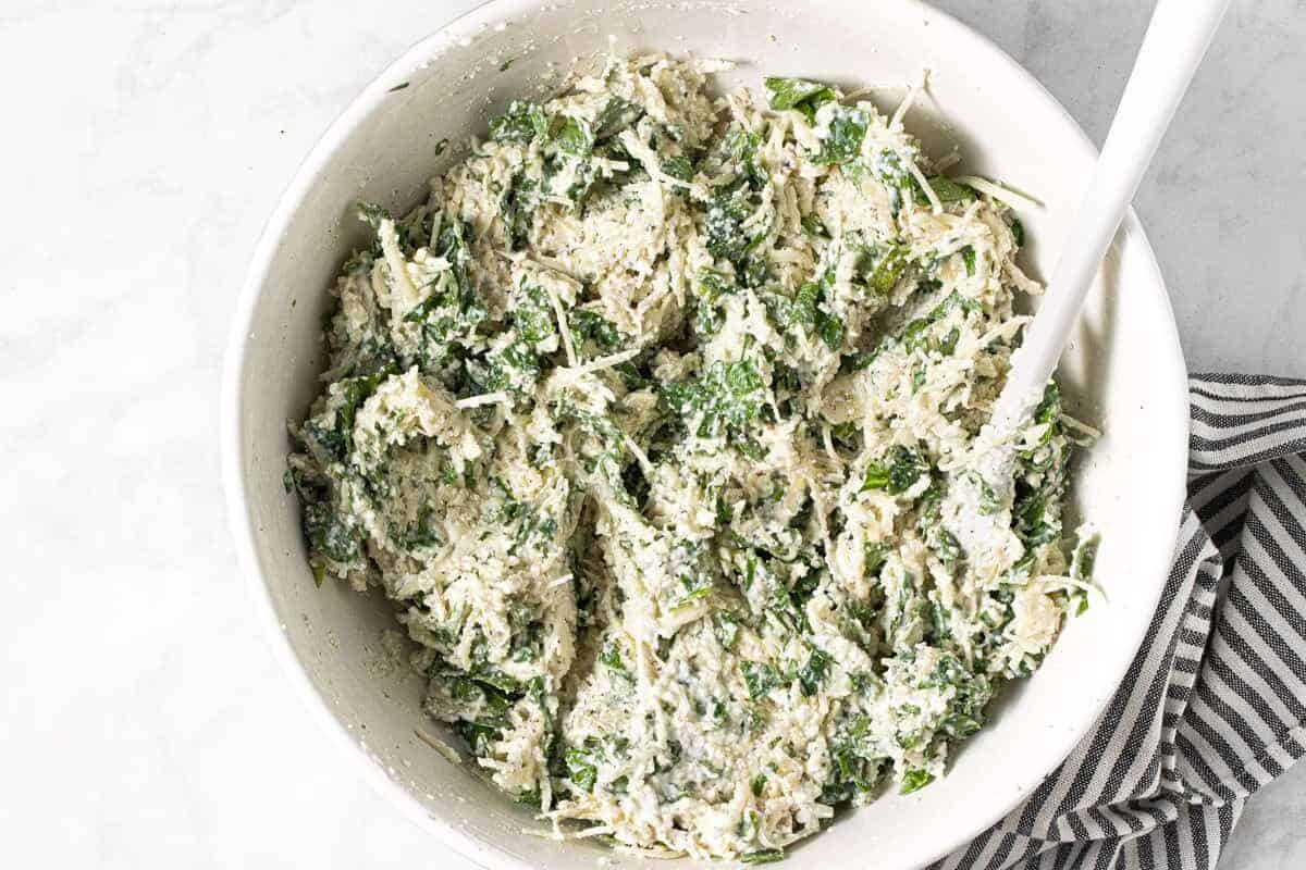 Large white bowl with ingredients to make lasagna filling