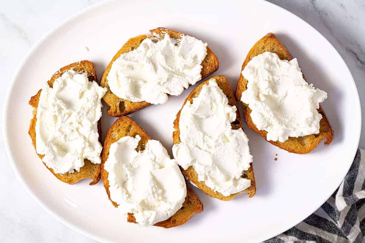 Large white platter with toast topped with creamy ricotta cheese