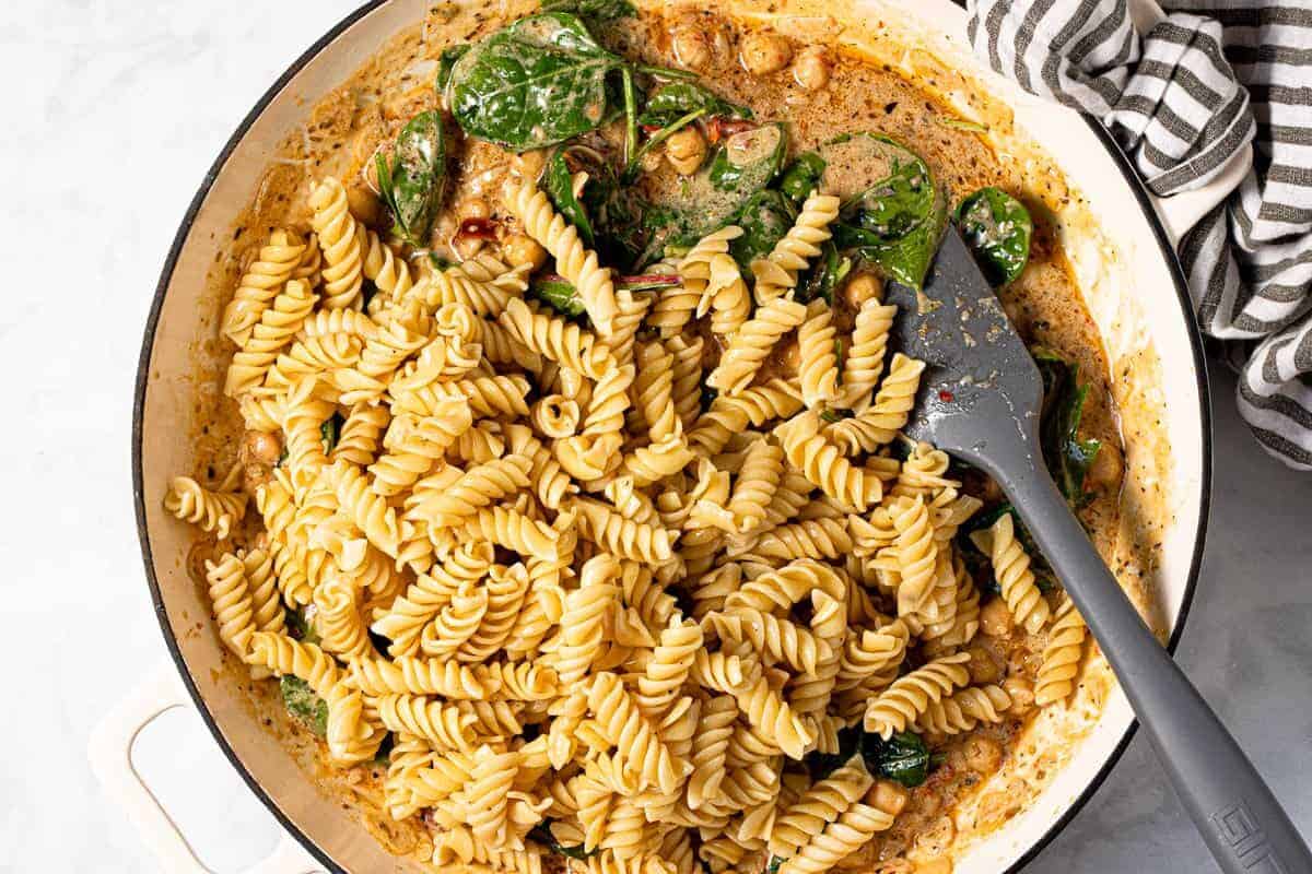 Large pan filled with creamy sun-dried tomato sauce and cooked pasta