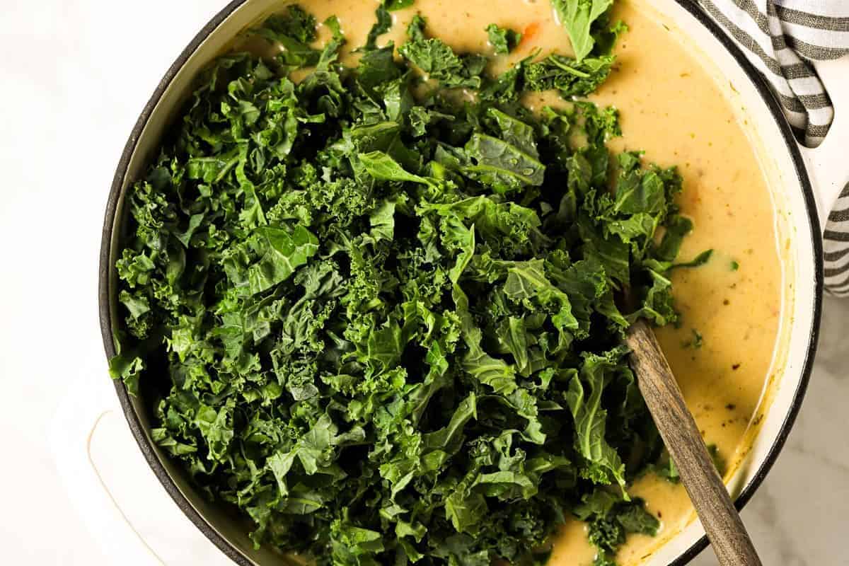 Large white pot with ingredients to make potato kale soup