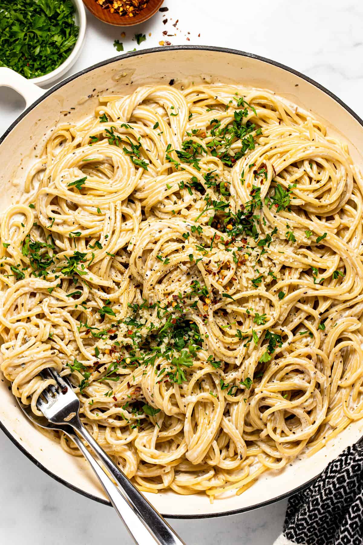 Large white pan filled with garlic Parmesan pasta topped with parsley