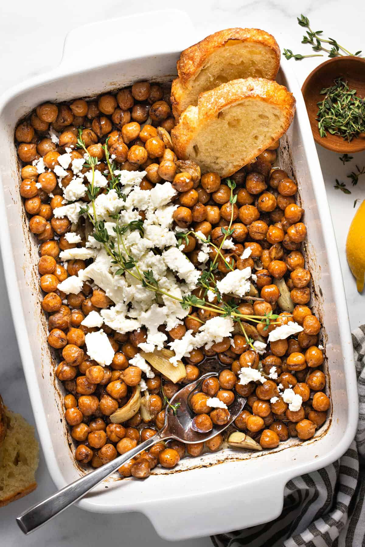 Large baking dish filled with braised chickpeas topped with feta and herbs