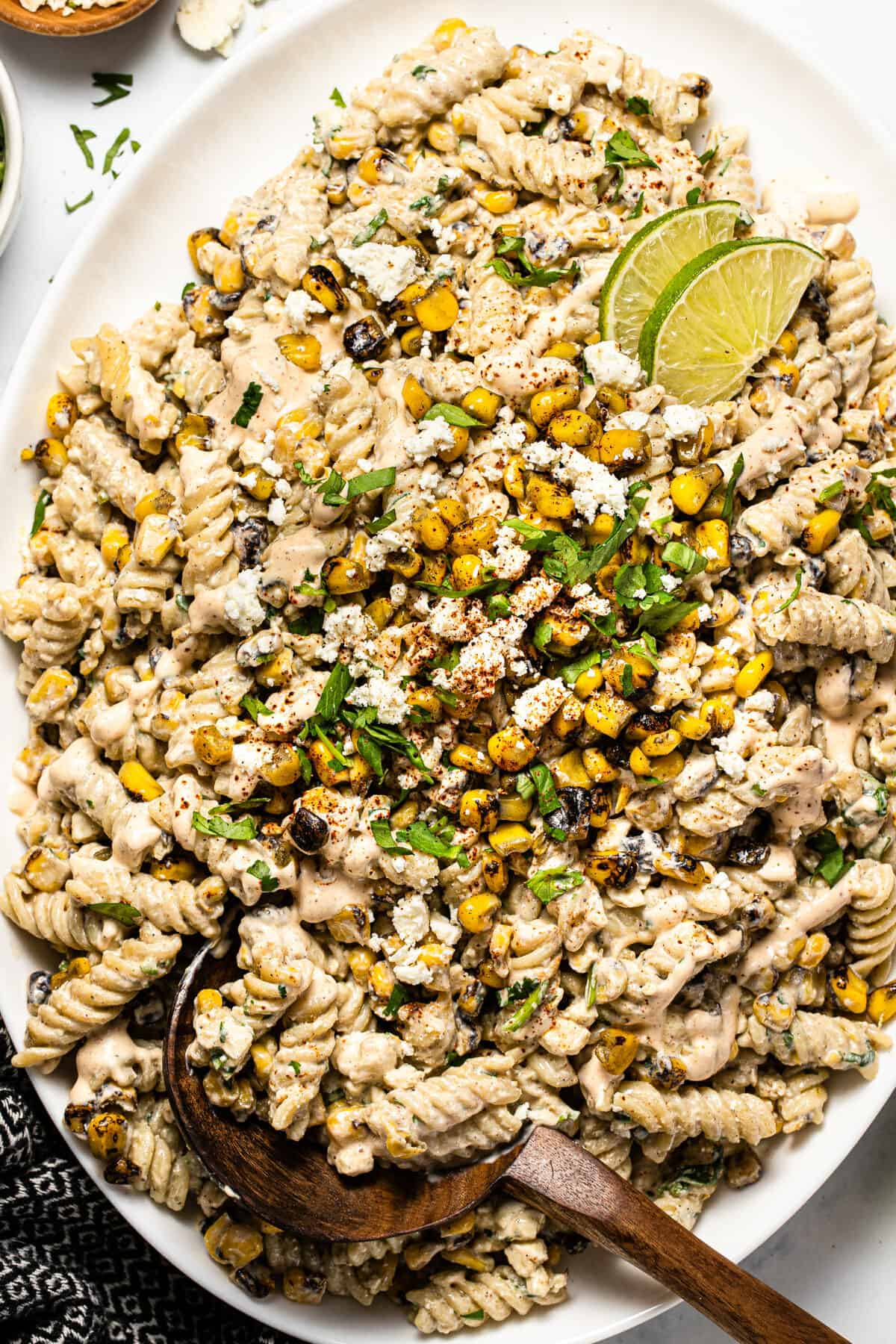 Overhead shot of a white platter filled with Mexican street corn pasta salad garnished with fresh cilantro 