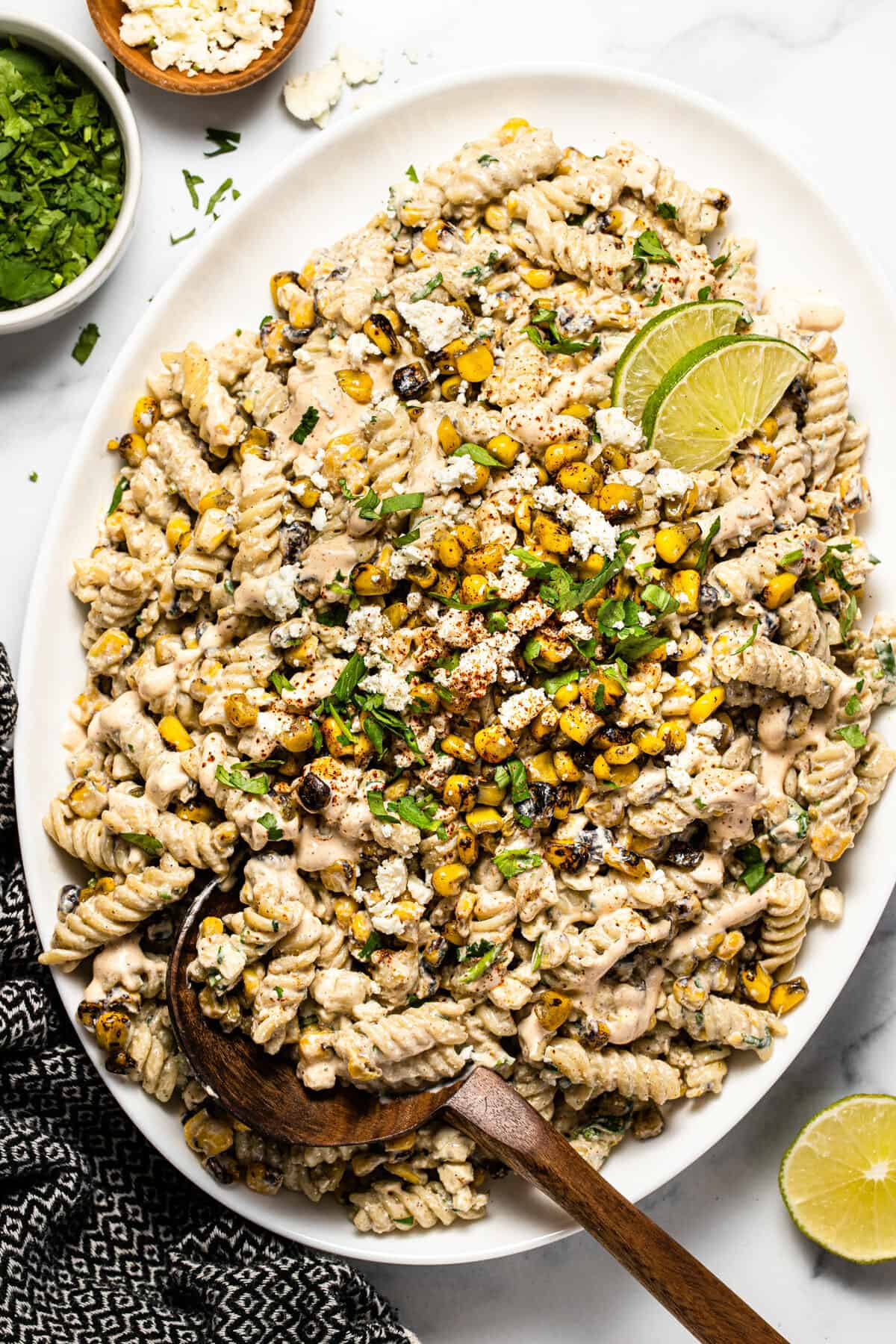 Overhead shot of a white platter filled with Mexican street corn pasta salad garnished with fresh cilantro 