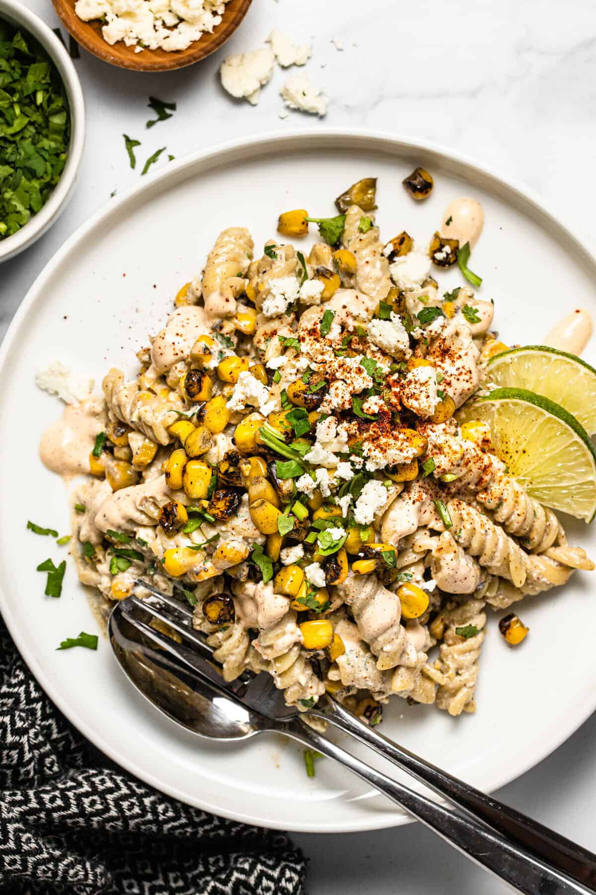 Overhead shot of a white plate filled with Mexican street corn pasta salad garnished with fresh cilantro 