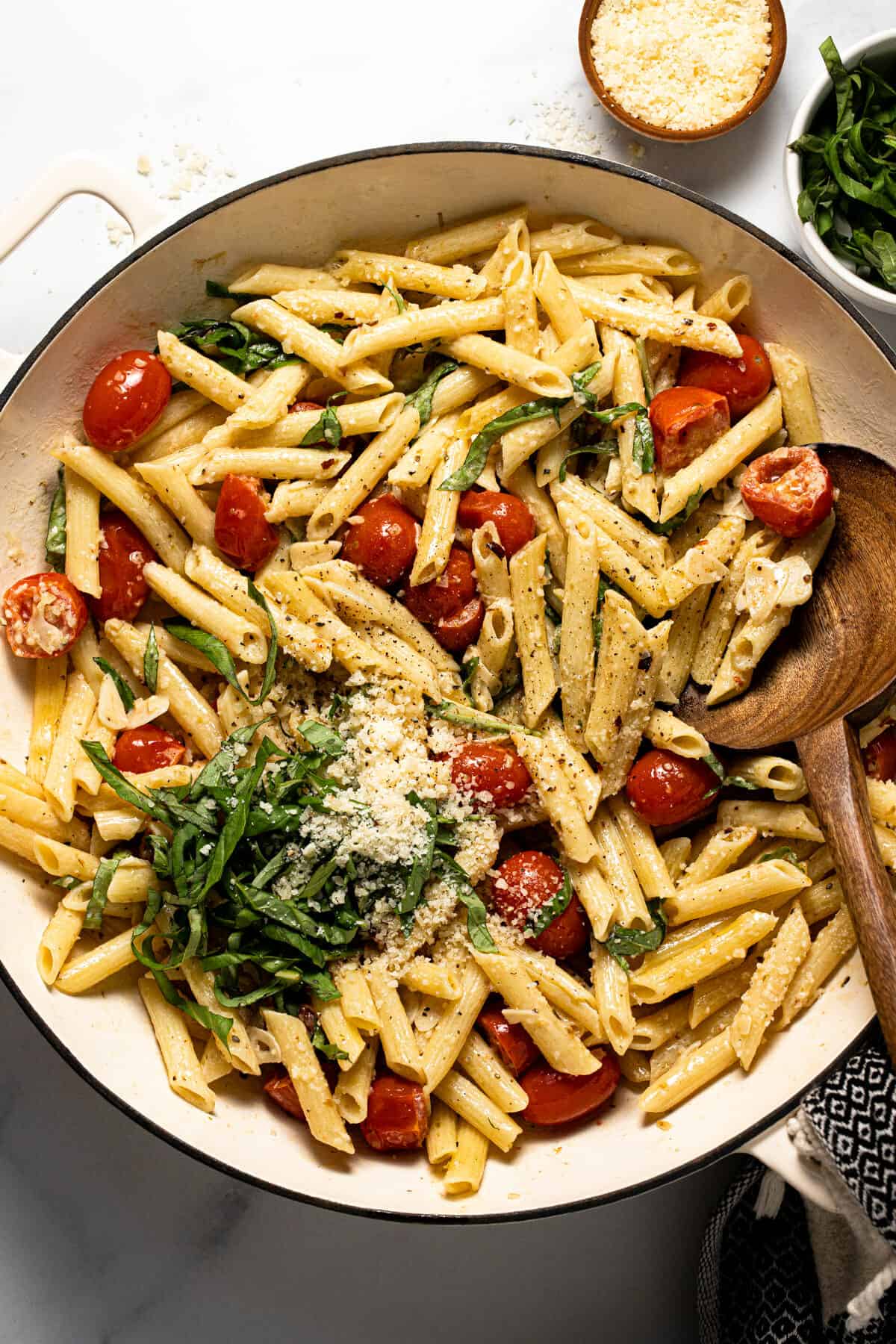 Large white pan filled with pasta with tomatoes and garlic white wine sauce