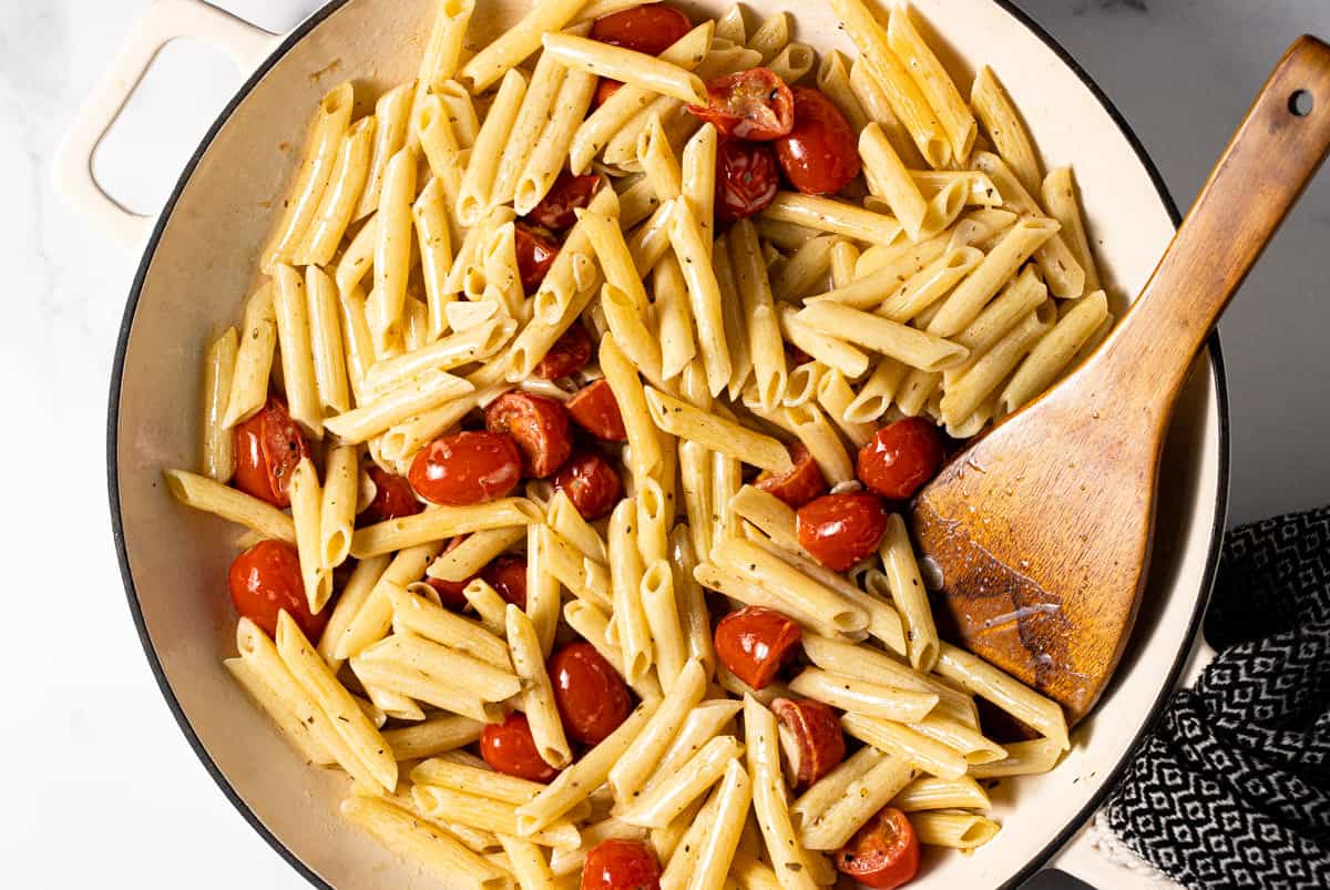 Large white pan filled with ingredients to make pasta with tomatoes and garlic cream sauce
